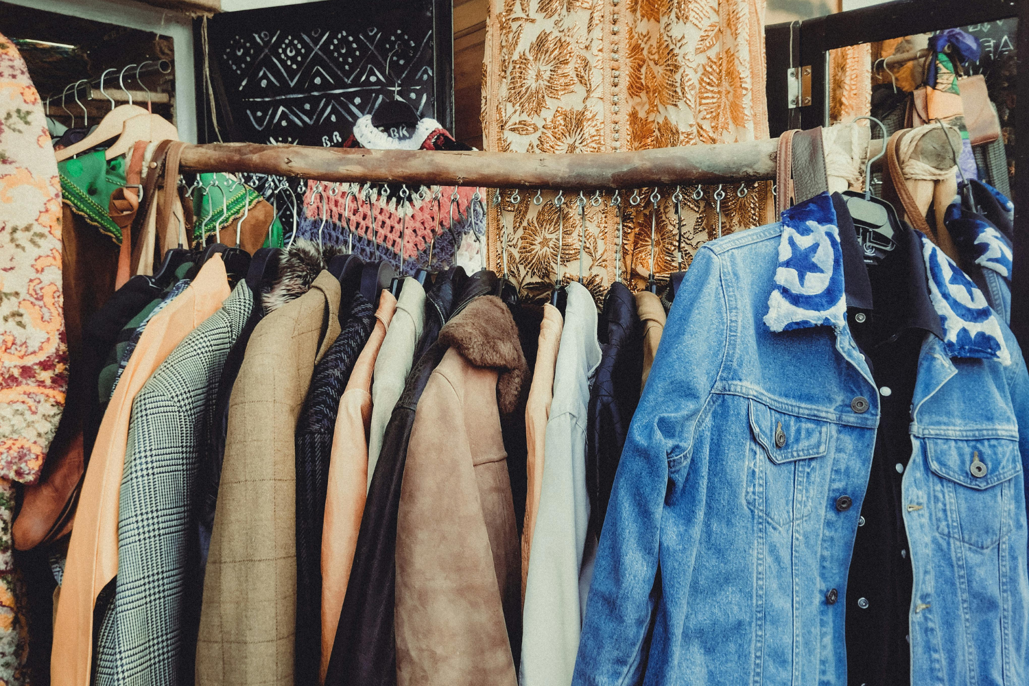 Rack of second‑hand jackets and coats displayed in a vintage or thrift shop, representing reuse and circular fashion.