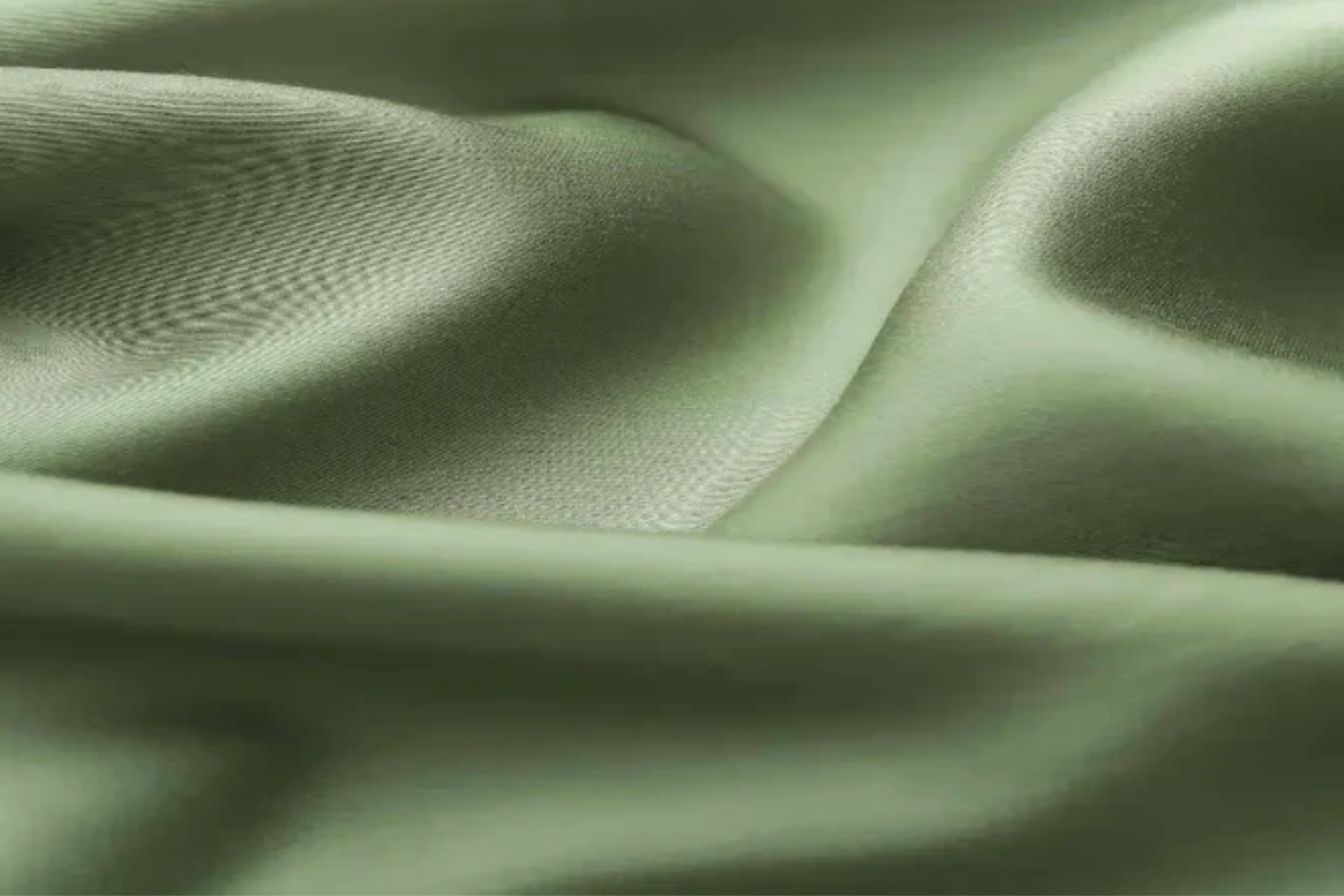 Close-up of soft, light-green fabric with a smooth, flowing texture and subtle sheen.