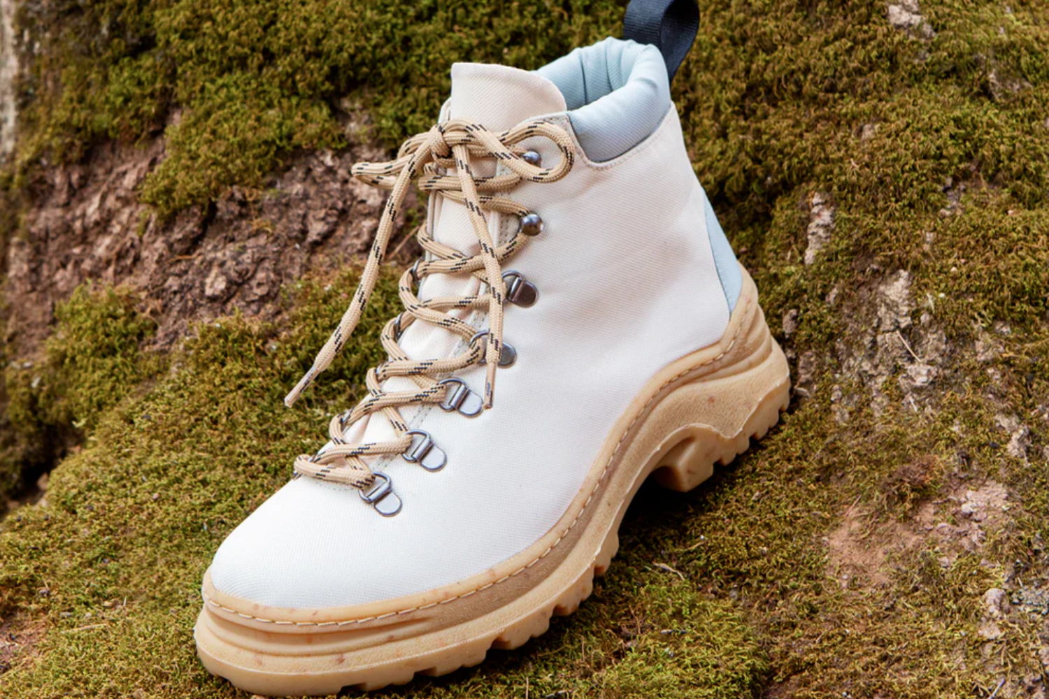 Sustainable hiking-style boot in neutral tones resting on a mossy forest floor