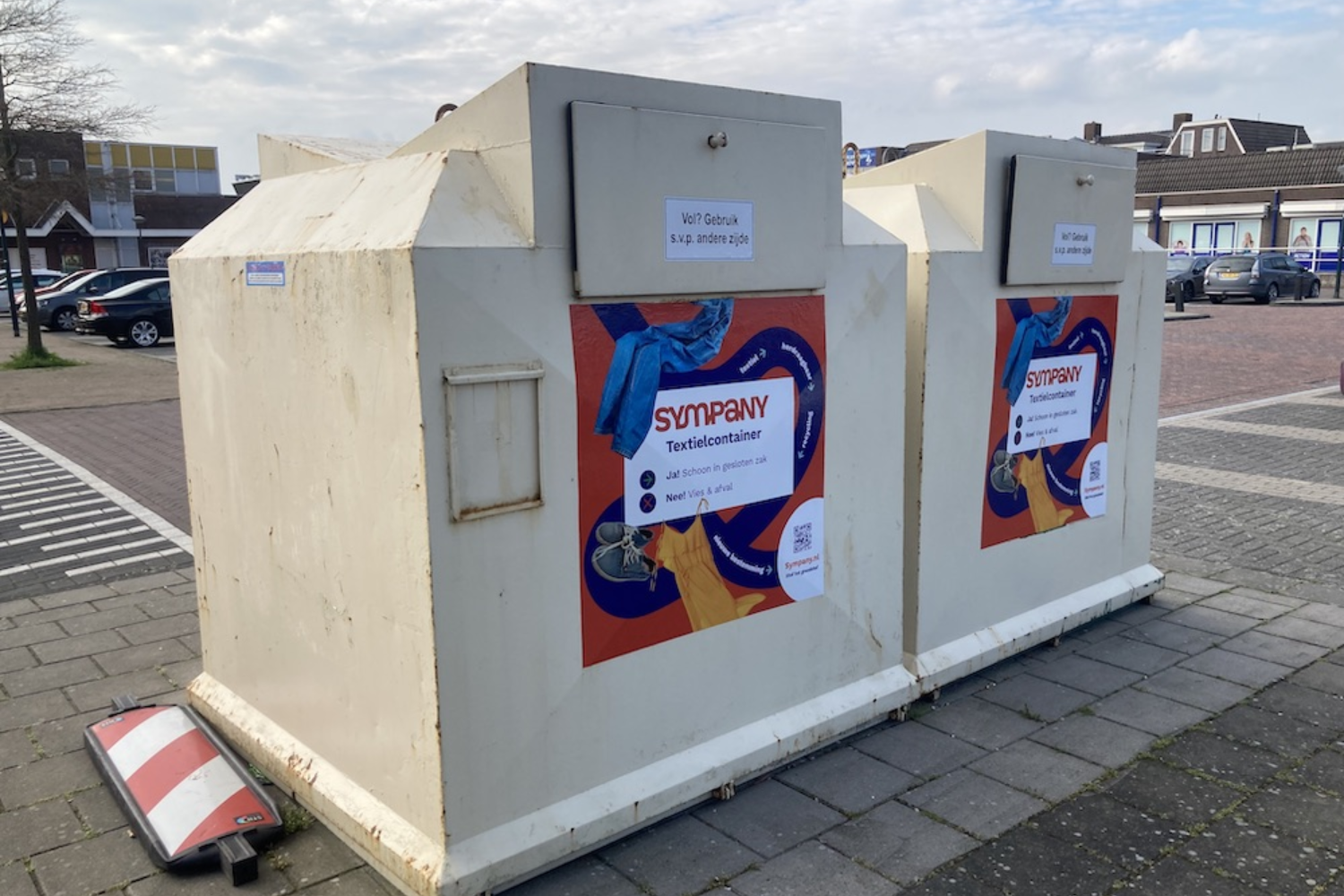 Public textile recycling containers placed outdoors, used for collecting clothes and shoes for reuse or recycling.