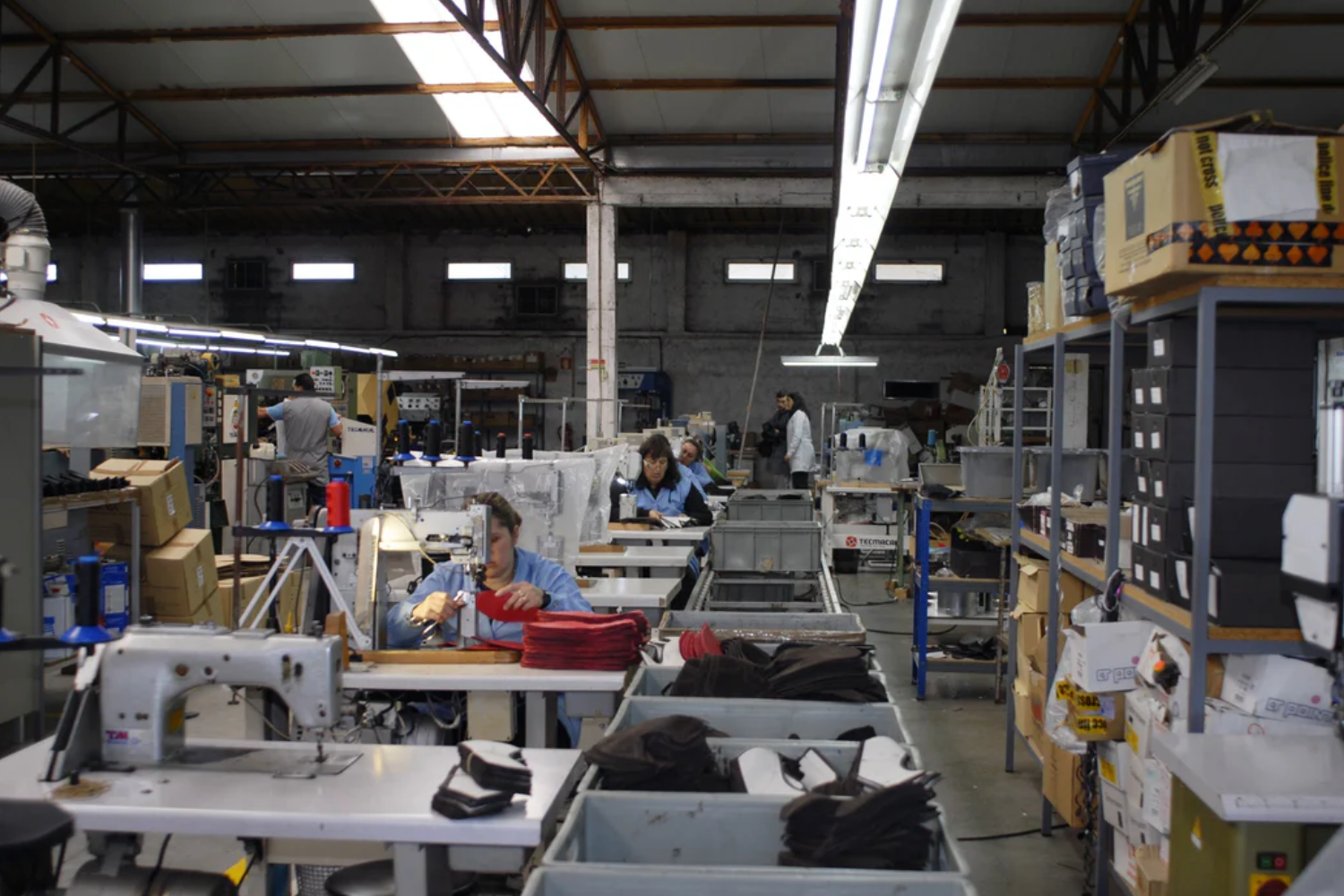 Interior of a shoe production facility with workers sewing and assembling components, reflecting small-batch ethical manufacturing.