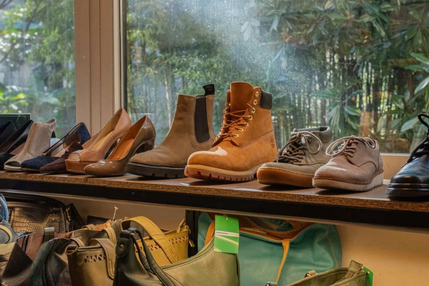A selection of secondhand shoes displayed on a shelf, including winter boots and dress shoes