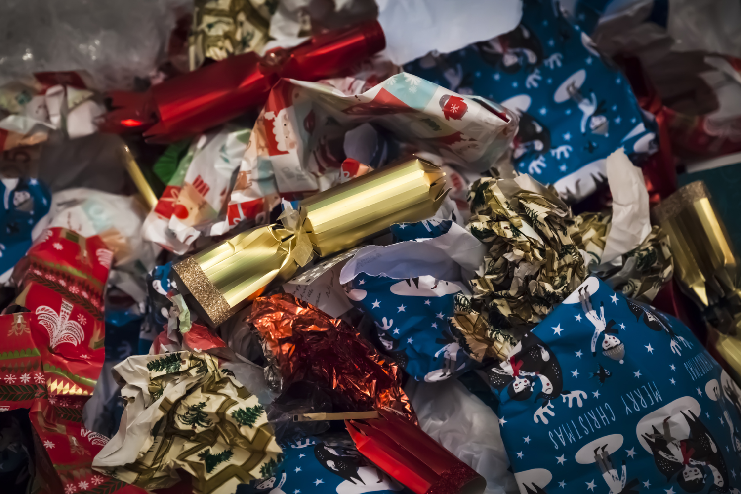 Pile of crumpled Christmas wrapping paper, foil, and gift packaging showing holiday waste.